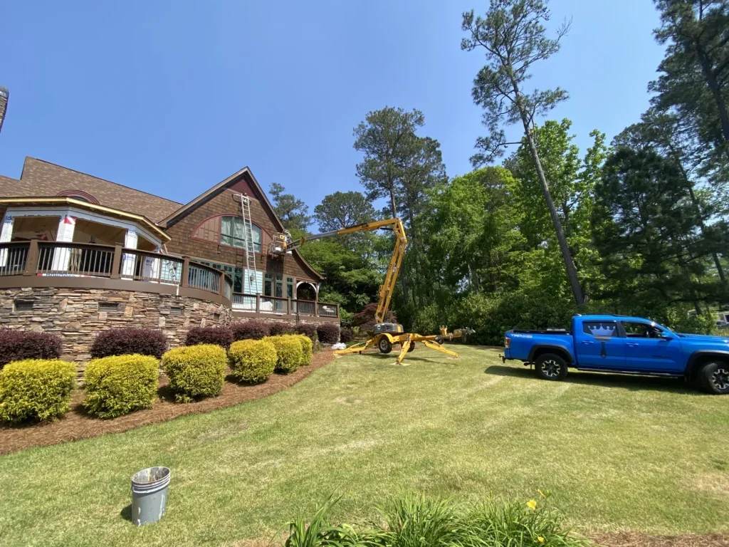 Painters Touch truck and boom lift beside a large house during exterior painting